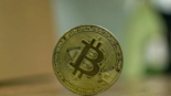 close-up of a physical Bitcoin coin placed upright on a table symbolizing the transition from cryptocurrency speculation to blockchain-based fixed income