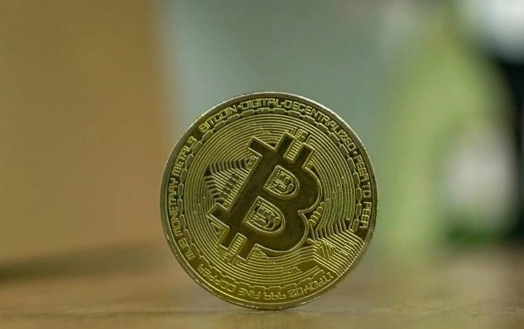 close-up of a physical Bitcoin coin placed upright on a table symbolizing the transition from cryptocurrency speculation to blockchain-based fixed income